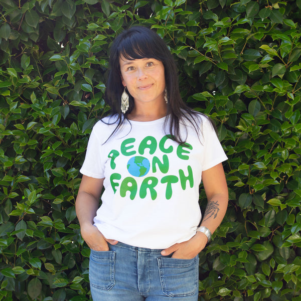 Smiling woman wearing a peac on earth t-shirt with a drawing of the globe