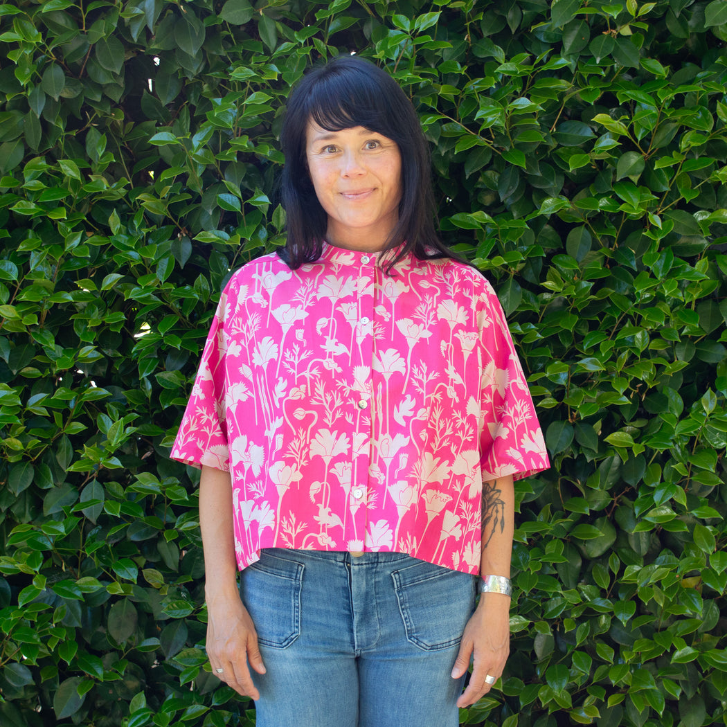 Happy woman wears a raspberry pink California printed poppy button down shirt